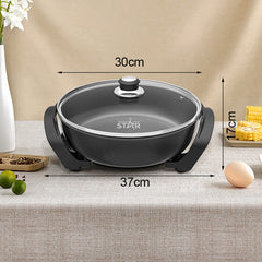 Black electric skillet with glass lid, shown on a beige tablecloth with dimension arrows indicating 30cm width, 37cm diameter, and 17cm height. Decorative props include flowers, limes, corn, and an egg.