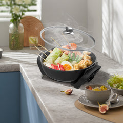 Electric frying pan with skewered food on a kitchen counter
